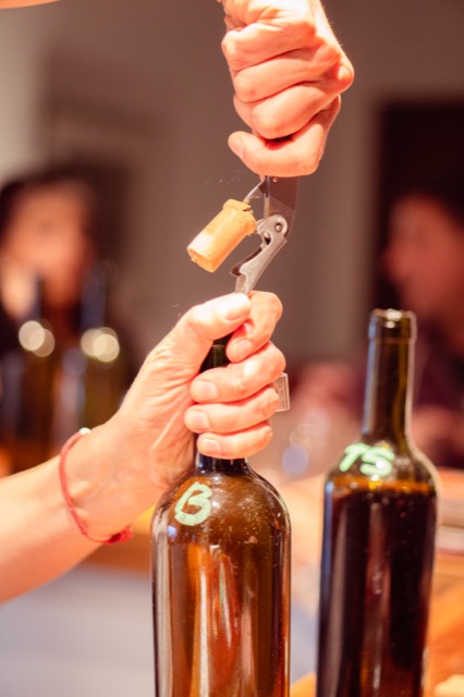 Manos descorchando una botella para compartir